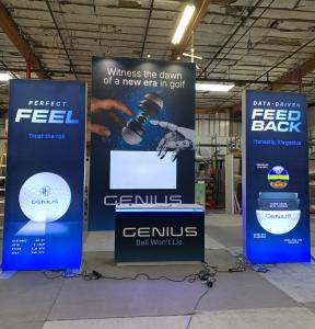 RENTAL: Island Design with 118" Wide x 42" Deep x 190" High Gravitee Storage Tower, (4) Large Monitor Mounts, (2) 85" Monitors, (2) 50" Monitors, (2) RE-1608 4 ft. Wide x 10 ft. High Double-Sided Lightboxes, RE-1577 Reception Counter, (6) LED Arm Lights,